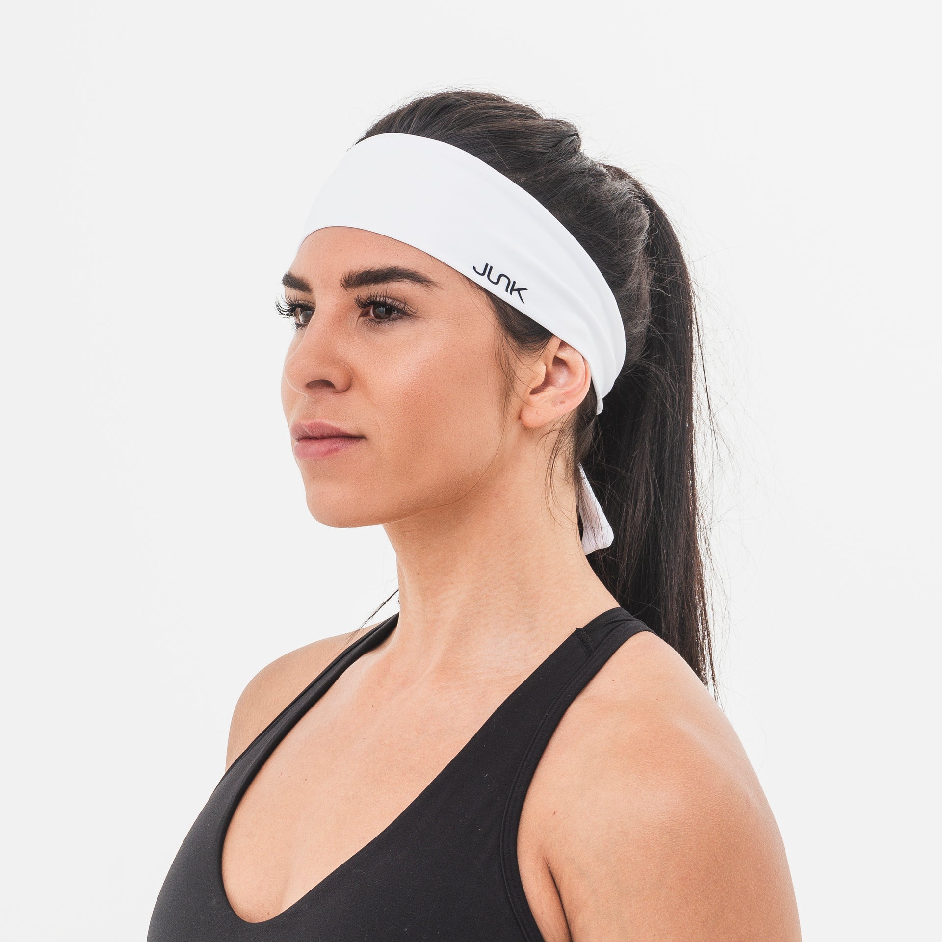 Woman wearing a white Flex Tie headband with 'JUNK' branding on a light gray background