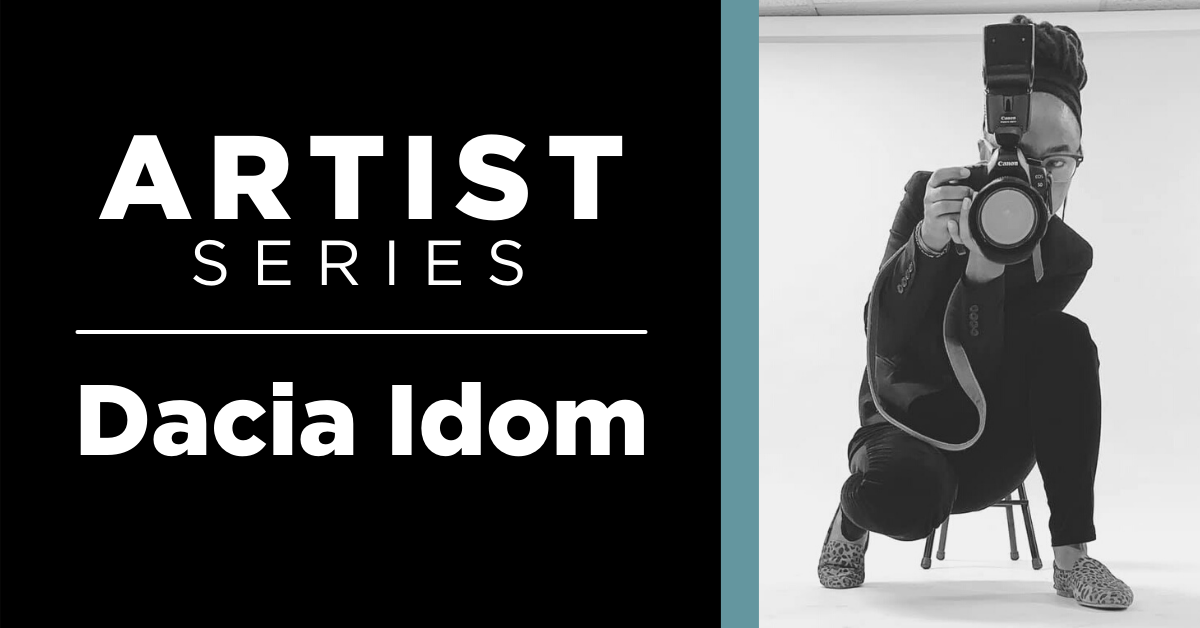 Image of Dacia Idom holding a camera like she is taking the photo, there is a stool behind her and white background. Text reads Artist series – Dacia Idom. 