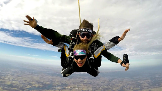 Skydiving pro and JUNKie mid-sky as they dive, smiling at the camera in their JUNK headbands.