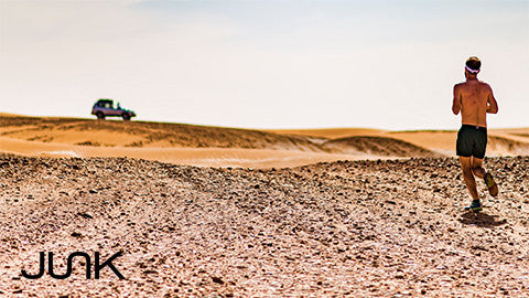Man runs in desert towards vehicle in distance