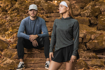 Two people in athletic wear sitting on stone steps with a natural background